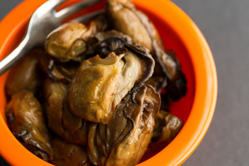 Close view of small whole smoked oysters with fork