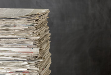 Zeitungsstapel vor einem dunklen Hintergund