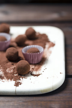 Chocolate truffles and cacao powder on wooden board