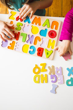 Two sisters with  wooden alphabet puzzle