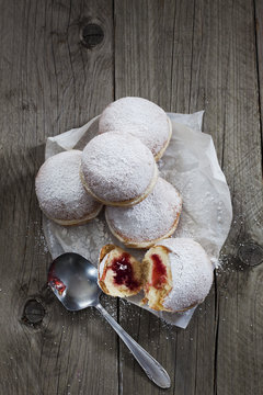 Five Bismarck doughnuts on paper and grey wood