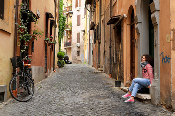 Fototapeta na wymiar Girl is sitting at home on a small Italian street