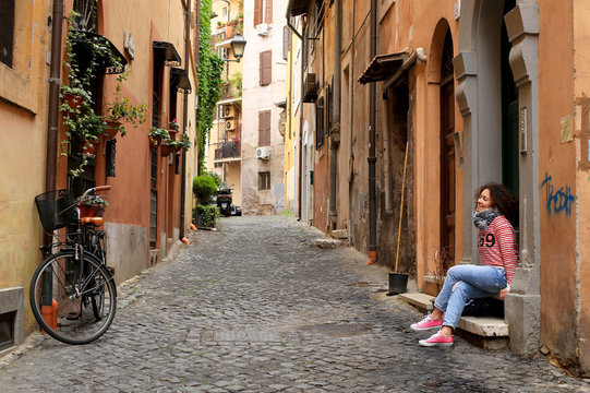 Girl is sitting at home on a small Italian street