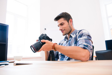 Happy man sitting at the table with photo camera