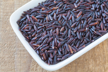 Healthy food uncooked brown rice in white bowl on wood background