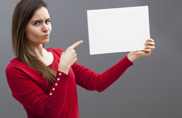 judge mental young lady pointing at a blank message on board and wearing a red sweater