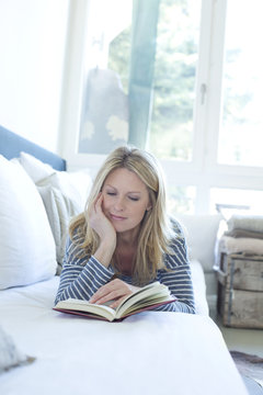 Woman lying on couch reading a book