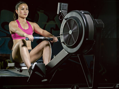 Young woman exercising at rowing machine