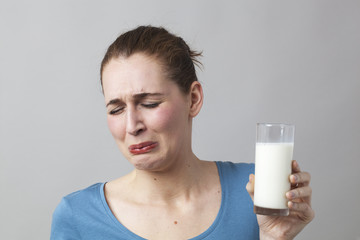 nauseous young woman panicking at the idea of drinking a glass of smelly milk or disgusting white...