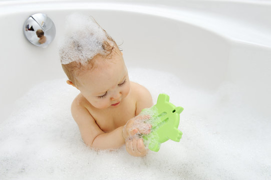 Baby girl with thermometer in a bathtub