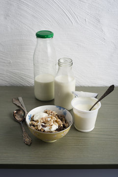 Bowl of granola, bottles of milk and cup of natural yoghurt