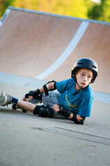 young boy learning to skateboard falls over