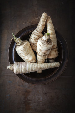 Bowl of parsley roots on dark wood