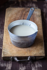 Latte di farro in un pentolino su tagliere in legno