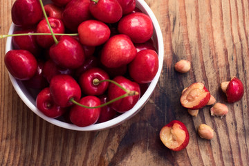 Ripe organic homegrown cherries and stones in a vintage ceramic bowl, on wooden background