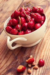 Ripe organic homegrown cherries and stones in a vintage ceramic bowl, on wooden background