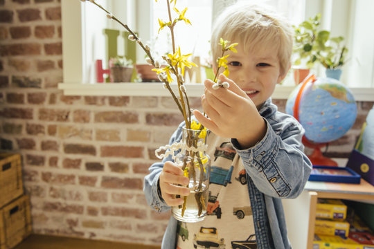 Little boy holding vase with willow catkin and forsythia