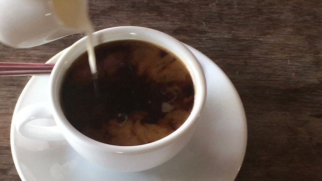Pouring milk into coffee cup, stock video
