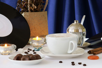 Cappuccino coffee in a cup,coffee beans and candles on a table