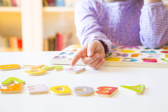 Little girl learning alphabet with wooden letters