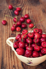 Ripe organic homegrown cherries in a vintage ceramic bowl, on wooden background