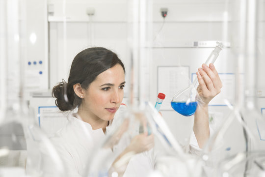 Young scientist in laboratory judging blue liquid in flask