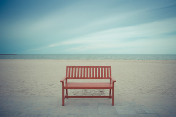 Alone wooden red beach chair sitting on the sand with sea.vintage color
