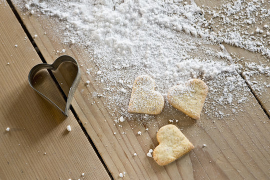 Heart-shaped shortbreads, icing sugar and cookie cutter