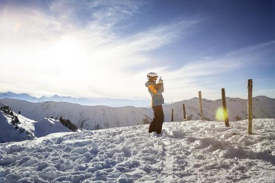 Austria, Salzburg State, Hochkoenig Region, young female skier taking picture with smartphone
