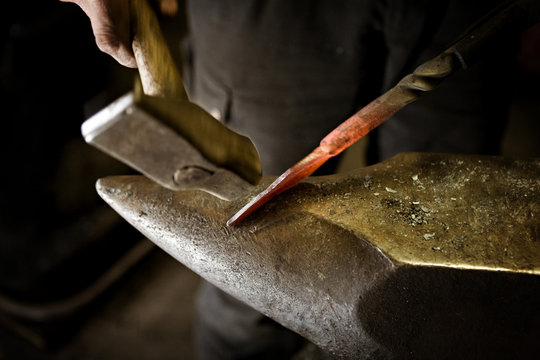 Blacksmith working with hammer at anvil