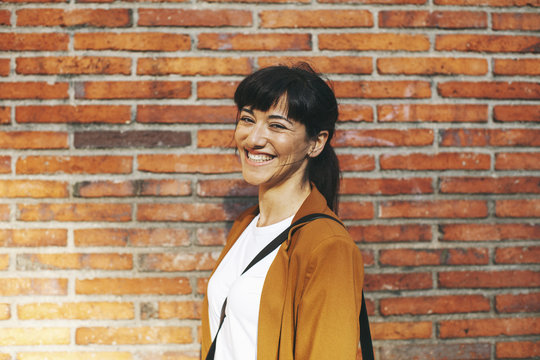Portrait of laughing businesswoman in front of a brick wall