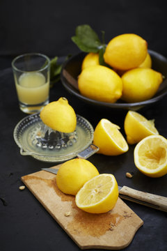 Sliced lemons in chopping board and freshly squeezed lemon juice