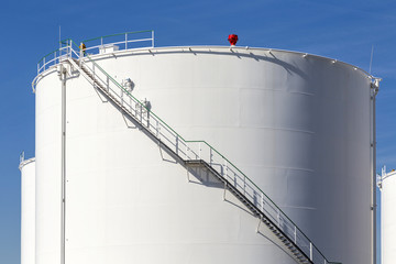 white tanks in tank farm with iron staircase