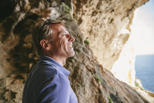 Spain, Mallorca, Arta, man standing inside a cave looking at view