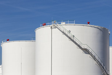 white tanks in tank farm with iron staircase