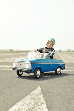 Smiling boy in pedal car on race track