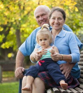mature couple with child sitting on bench