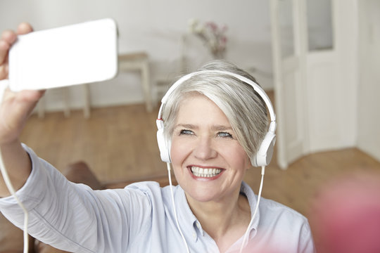 Mature woman wearing headphones taking selfie