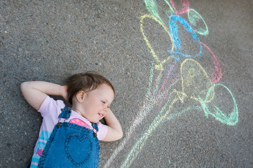 Naklejka premium Little Girl with balloons, drawing with chalk on the pavement