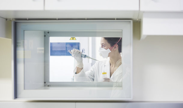 Young lab technician wearing mask pipetting