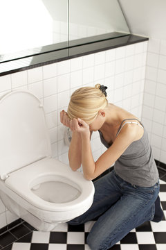 Despaired anorexic young woman at the toilet