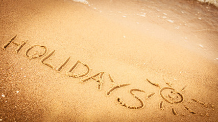 The word holidays written in the sand on a beach