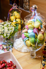 Large glass vase with sweets/Glass vase with lemons and macaroon on a table with flowers