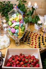 Macaroon, strawberries and cookies on the French party/Macaroon in a glass vase and other sweets at a party in the French style