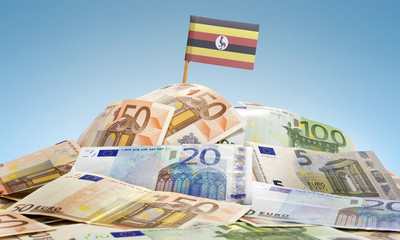 Flag of Uganda sticking in a pile of various european banknotes.