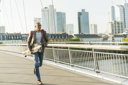 Germany, Frankfurt, man running with skateboard on bridge