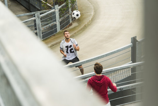Two young men heading soccer ball over fence