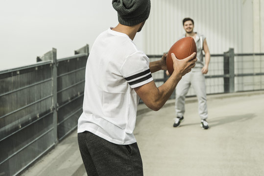 Two young men playing with football on road