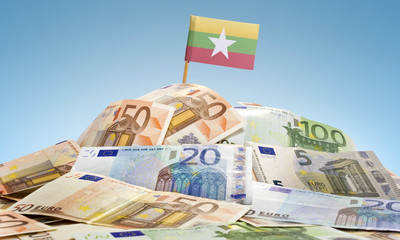 Flag of Burma sticking in a pile of various european banknotes.(