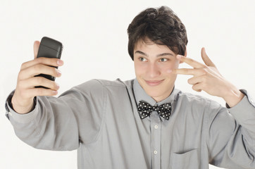 Naklejka premium Happy businessman taking a selfie photo with his smart phone. Conceited elegant man holding mobile phone signing victory. 